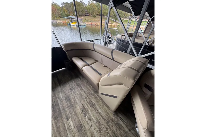 Slide: The Image of 2023 Crest Classic LX 220 pontoon boat with beige seating and lake view. - 8