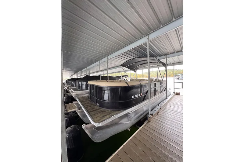 The Image of 2023 Crest Classic LX 220 pontoon boat docked under a covered marina. - 0
