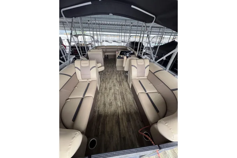 Slide: The Image of 2023 Crest Classic LX 220 pontoon boat interior with beige seating and wood-style flooring. - 3
