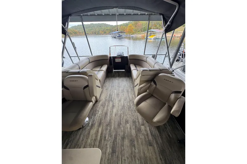 Slide: The Image of 2023 Crest Classic LX 220 pontoon boat interior with plush seating and scenic lake view. - 7