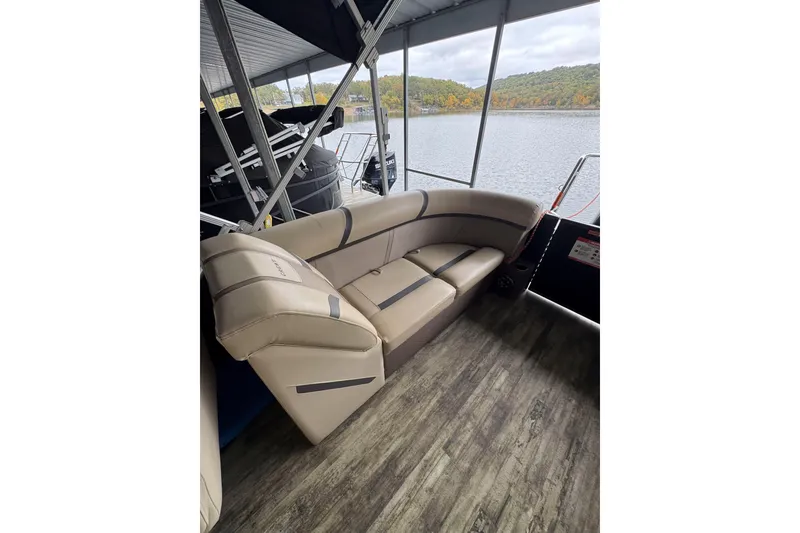 Slide: The Image of 2023 Crest Classic LX 220 pontoon boat interior with beige seating and lake view. - 9