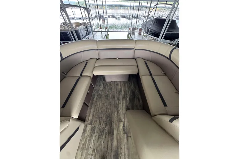 Slide: The Image of 2023 Crest Classic LX 220 pontoon boat interior with beige seating and wood-style flooring. - 6