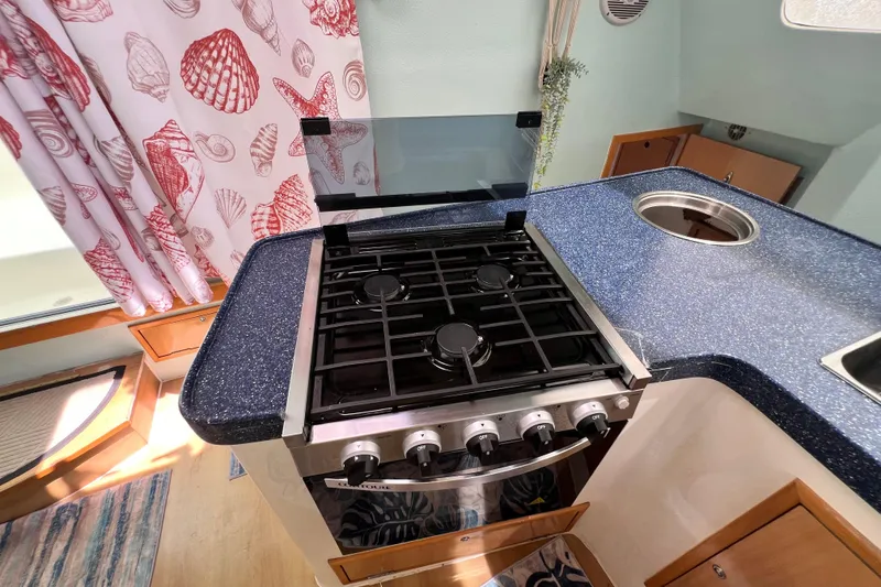 Slide: The Image of Modern kitchen in 2008 Admiral 40 cruiser with stove and seashell-themed curtains. - 46