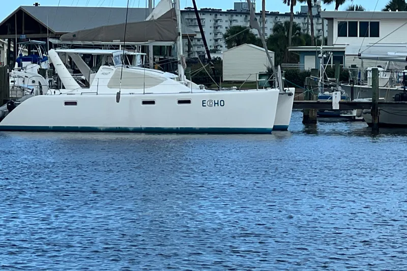 Slide: The Image of 2008 Admiral 40 Cruiser catamaran docked at marina, calm water, residential backdrop. - 3