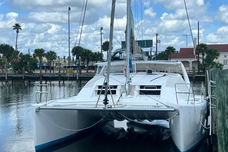 Slide: The Image of 2008 Admiral 40 Cruiser catamaran docked in a marina with palm trees and cloudy sky. - 5