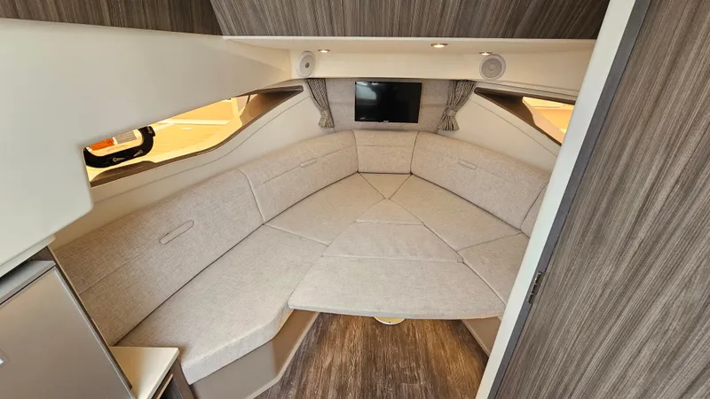 Slide: The Image of Interior of the 2025 Sea Ray Sundancer 320 Outboard with elegant seating area and small TV. - 20