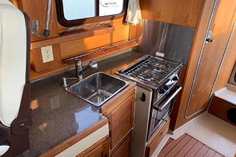 Slide: The Image of 2016 Ranger Tugs R-27 interior kitchen with sink, stove, and wooden cabinetry. - 12
