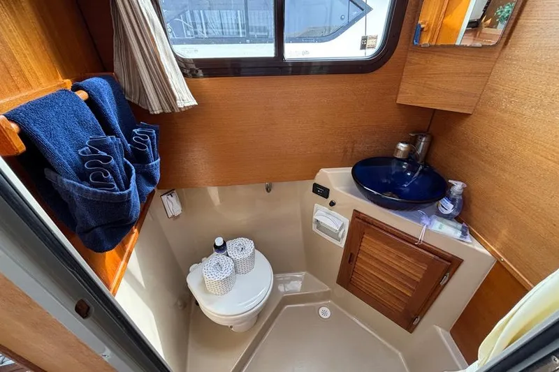 Slide: The Image of 2016 Ranger Tugs R-27 boat bathroom with wooden cabinetry and blue sink. - 5