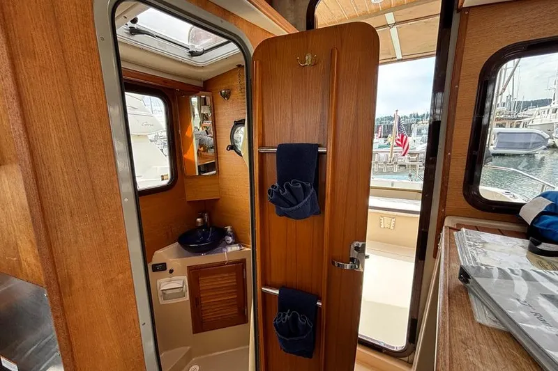 Slide: The Image of Interior of 2016 Ranger Tugs R-27 boat, featuring a compact bathroom and wooden cabinetry. - 6