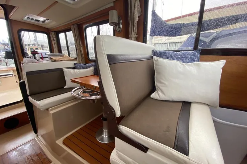 Slide: The Image of Interior of 2016 Ranger Tugs R-27 boat with cushioned seating and wooden accents. - 10