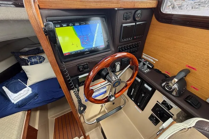 Slide: The Image of 2016 Ranger Tugs R-27 helm with GPS, wooden steering wheel, and navigation controls. - 7