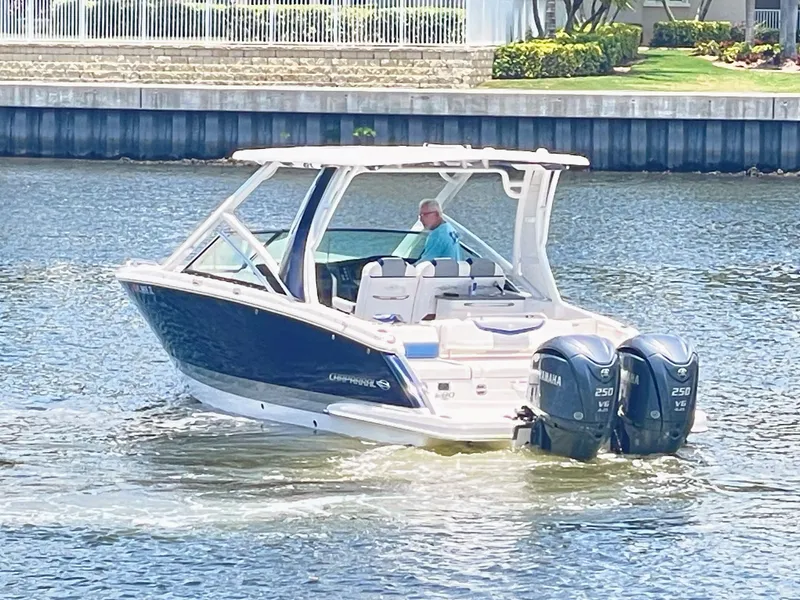 Slide: The Image of A 2023 Chaparral 280OSX boat cruising on calm water, featuring two outboard engines. - 2