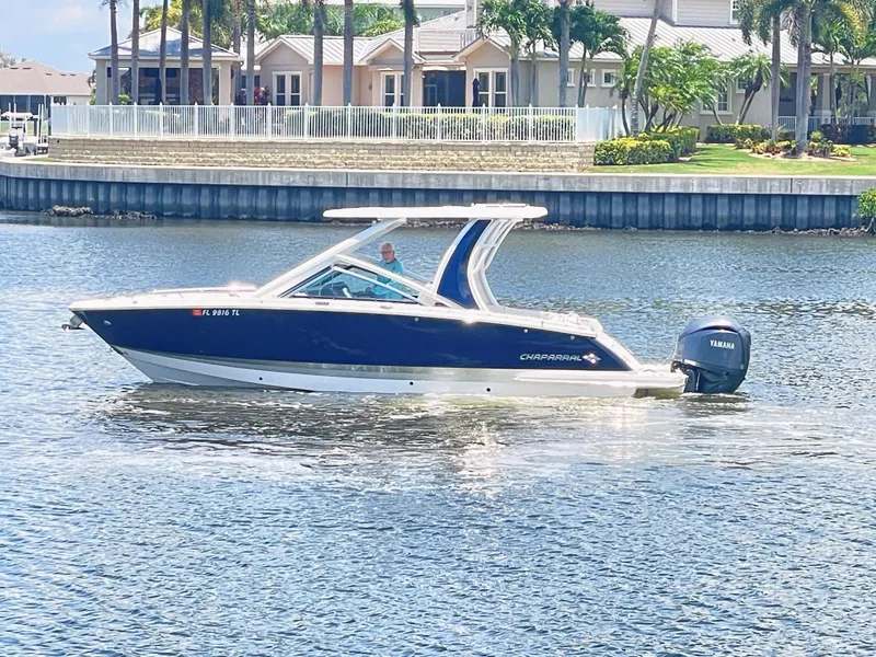 Slide: The Image of A 2023 Chaparral 280OSX boat on the water, featuring a blue hull and white roof. - 3