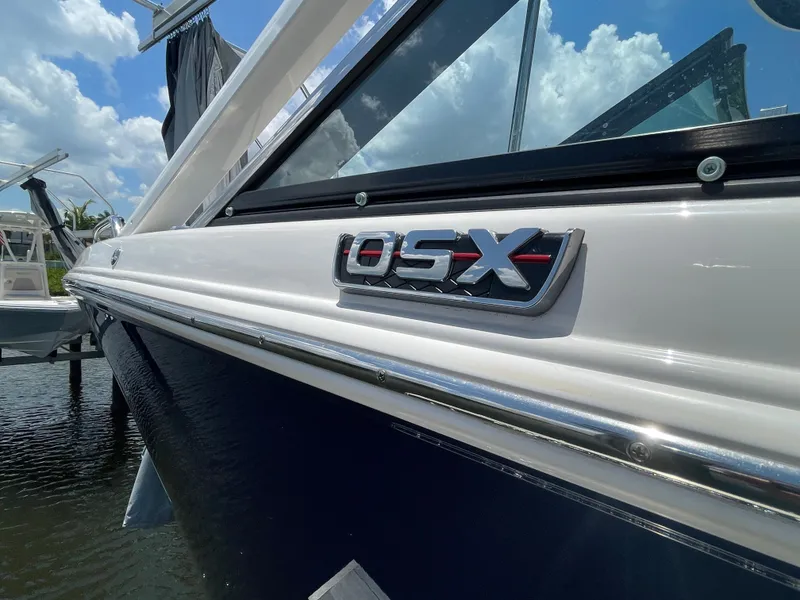 Slide: The Image of 2023 Chaparral 280OSX with sleek design, glossy hull, and distinctive logo by the water. - 22