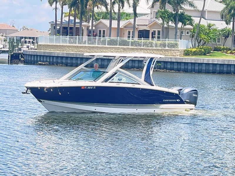 Slide: The Image of A 2023 Chaparral 280OSX boat cruising on calm waters near a residential area. - 1