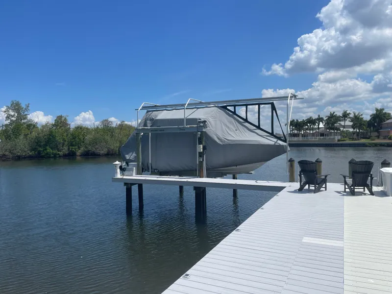 Slide: The Image of A covered boat on a lift at a serene dock with two chairs. - 6
