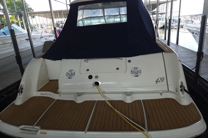 Slide: The Image of 2005 Sea Ray 420 Sundancer yacht docked, featuring a covered cockpit and teak swim platform. - 3