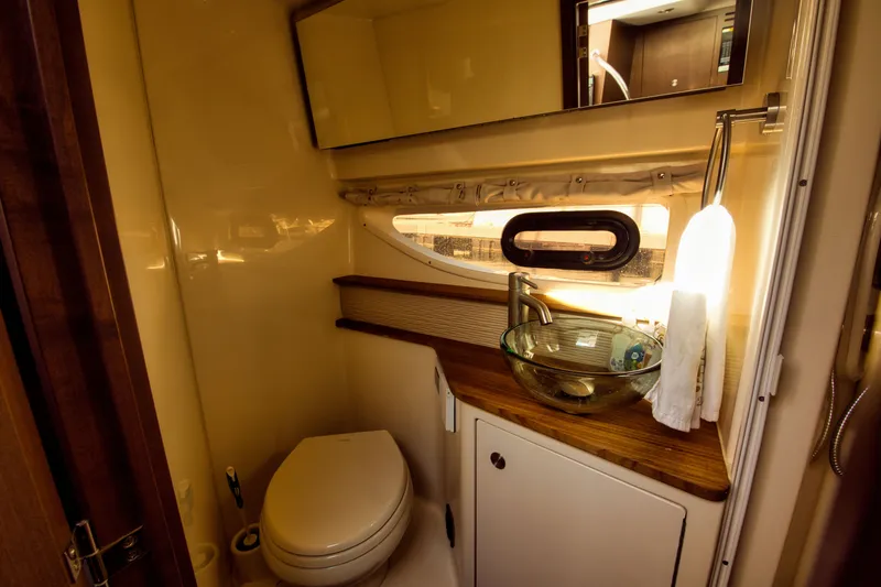 Slide: The Image of The image shows a sleek boat bathroom with a modern glass sink and a porthole. - 15