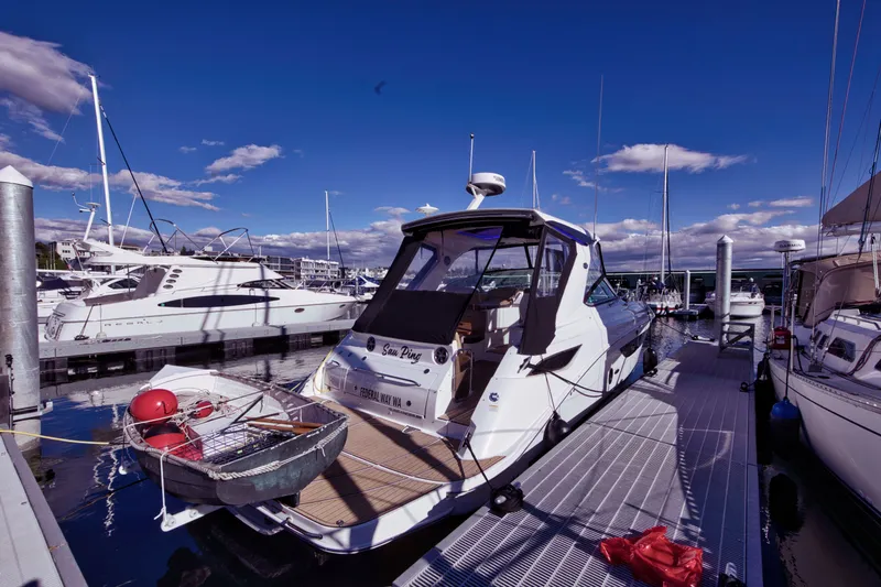 Slide: The Image of A 2021 Sea Ray Sundancer 350 docked at a marina. The sky is clear and blue. - 9