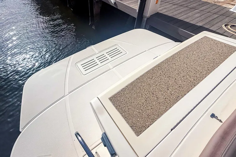 Slide: The Image of 2016 Sea Ray Sundancer 350 swim platform near dock, showcasing sleek design and water reflection. - 9