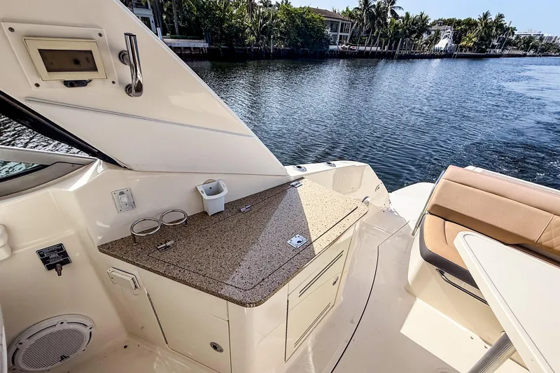 Slide: The Image of 2016 Sea Ray Sundancer 350 boat interior with countertop and seating by the water. - 14