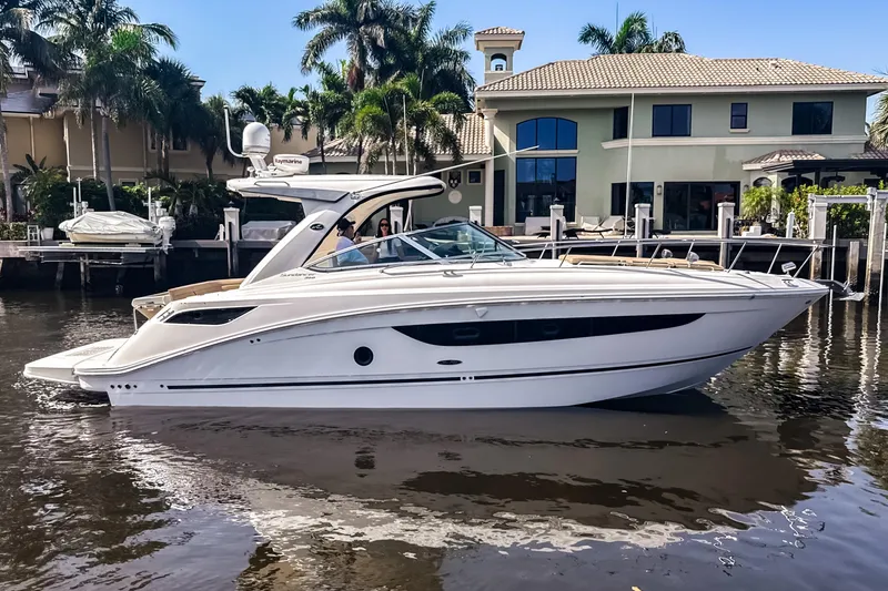 Slide: The Image of 2016 Sea Ray Sundancer 350 yacht docked near waterfront home, surrounded by palm trees. - 3