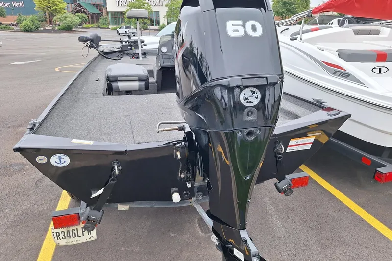 Slide: The Image of 2023 Lowe Skorpion 17 boat with a 60 HP outboard motor in a parking lot. - 17