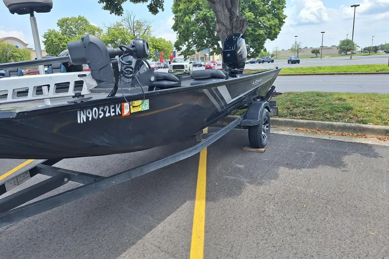 Slide: The Image of 2023 Lowe Skorpion 17 boat on trailer in parking lot, surrounded by trees and cars. - 9