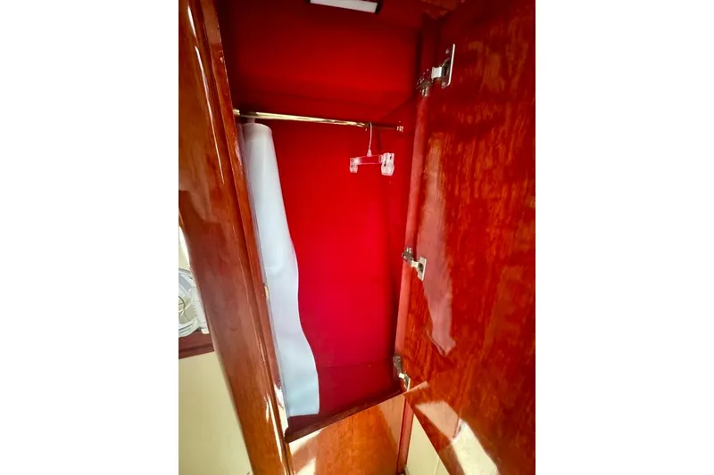 Slide: The Image of Wooden closet interior on Birchwood Challenger 450 Flybridge, 1999 model, with red lining and hanger. - 42