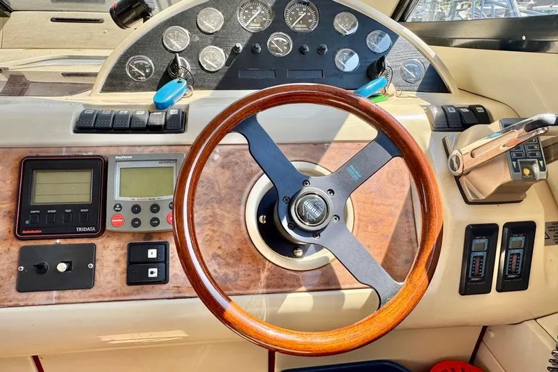 Slide: The Image of 1999 Birchwood Challenger 450 Flybridge helm with wooden steering wheel and navigation instruments. - 21