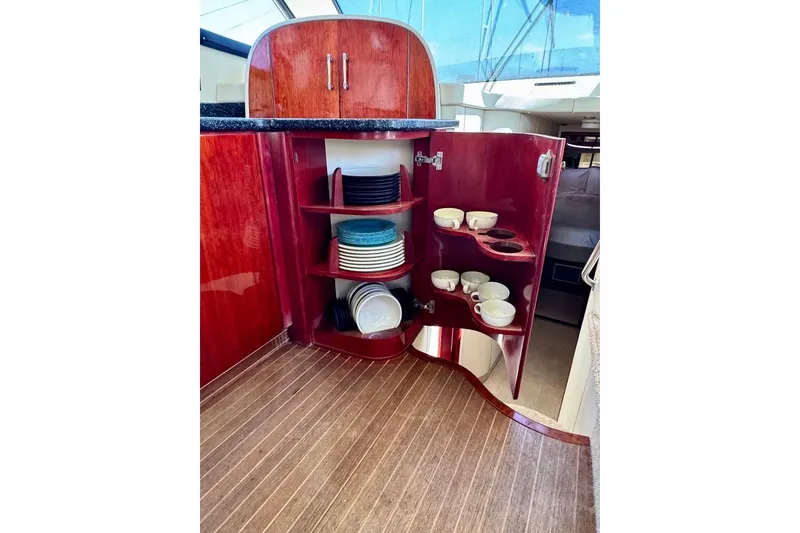 Slide: The Image of Interior of 1999 Birchwood Challenger 450 Flybridge with open cabinet displaying dishes and cups. - 27