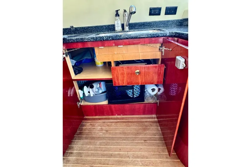 Slide: The Image of Open cabinet under sink on 1999 Birchwood Challenger 450 Flybridge, showing storage and cleaning supplies. - 29