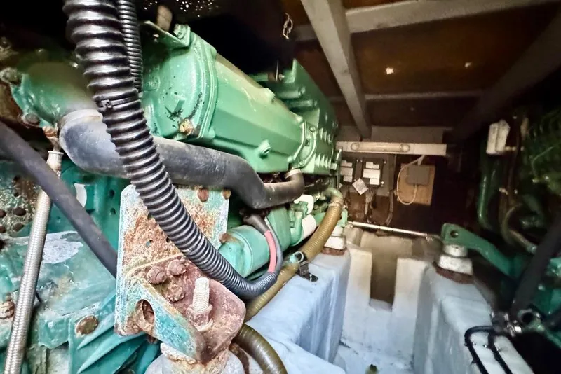 Slide: The Image of Engine room of 1999 Birchwood Challenger 450 Flybridge, showcasing green machinery and components. - 46