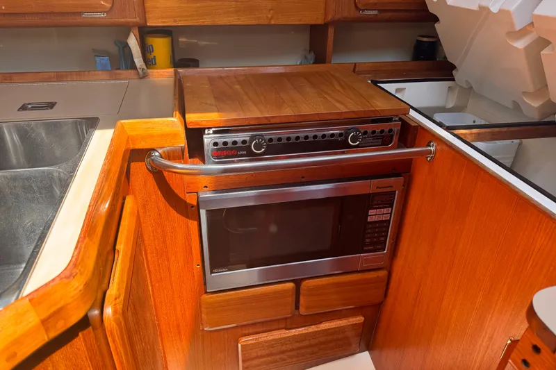 Slide: The Image of 1993 Hunter 33.5 yacht kitchen with stove, microwave, and wooden cabinetry. - 28
