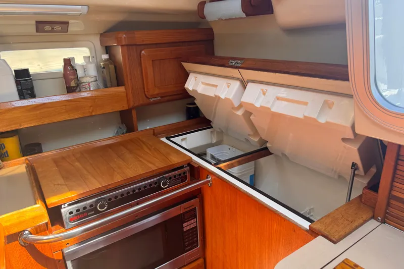 Slide: The Image of Interior of a 1993 Hunter 33.5 sailboat galley with wooden cabinetry and appliances. - 26
