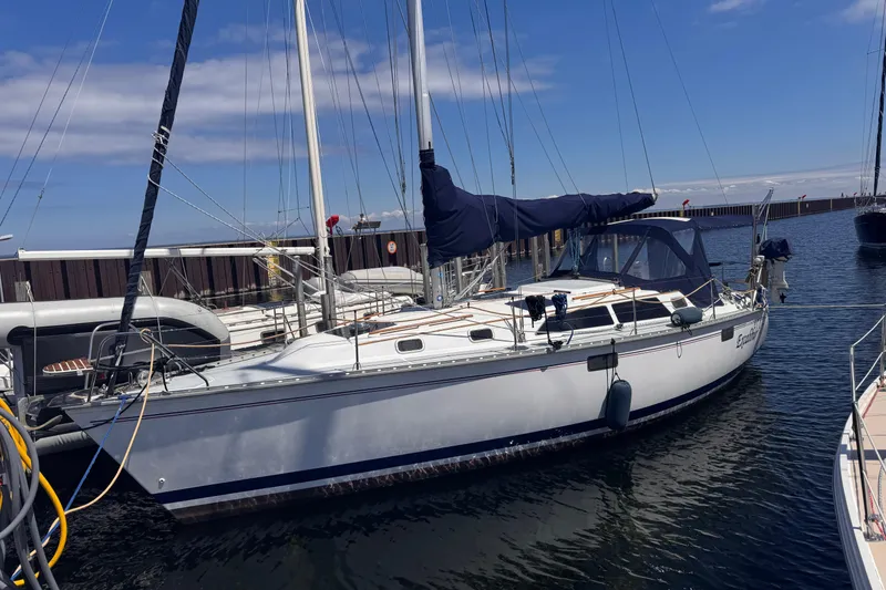 The Image of 1993 Hunter 33.5 sailboat docked at marina under clear blue sky. - 0