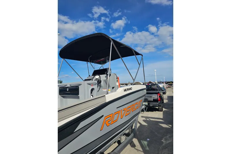 Slide: The Image of 2026 Murano 205 boat with canopy, parked on trailer under blue sky. - 24