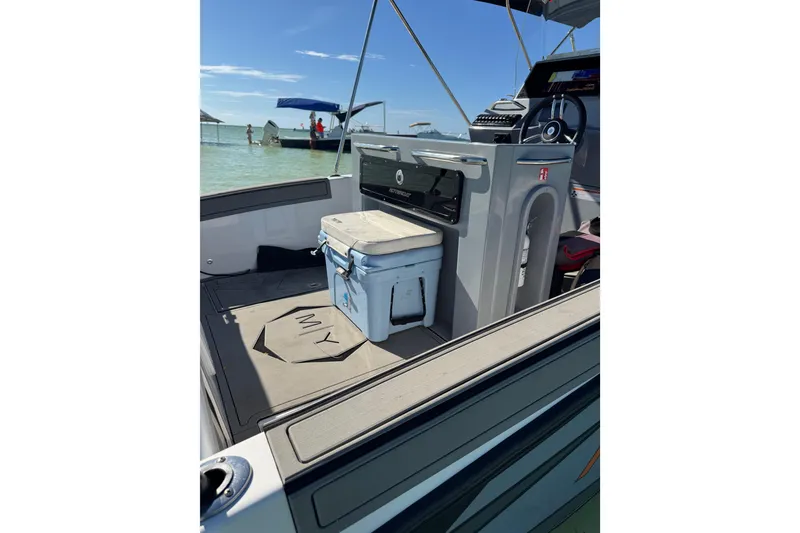 Slide: The Image of 2026 Murano 205 boat interior with cooler, steering console, and sunny beach background. - 7