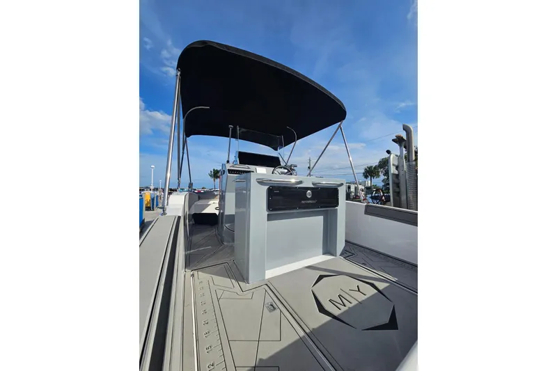Slide: The Image of 2026 Murano 205 boat interior with canopy, sleek design, and modern controls under a clear blue sky. - 31