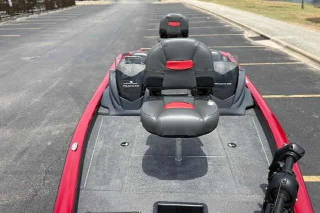Slide: The Image of 2025 Tracker Off Road Pro Team 175 boat with red and black seating, parked on pavement. - 30