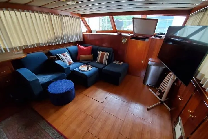 Slide: The Image of 1971 Monk 44 Express Bridge interior with blue seating, wood paneling, and large windows. - 2