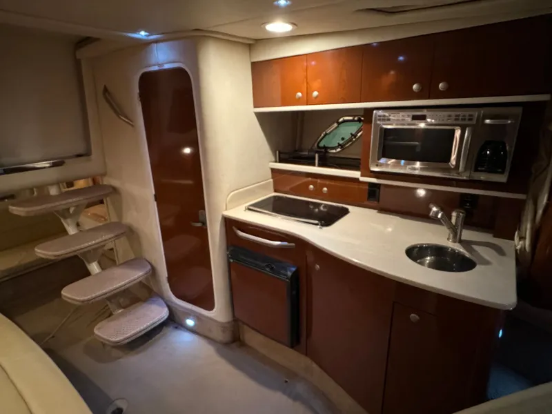 Slide: The Image of The interior of a 2008 Sea Ray Sundancer 310 features a well-equipped galley with sink, microwave, and fridge. - 33