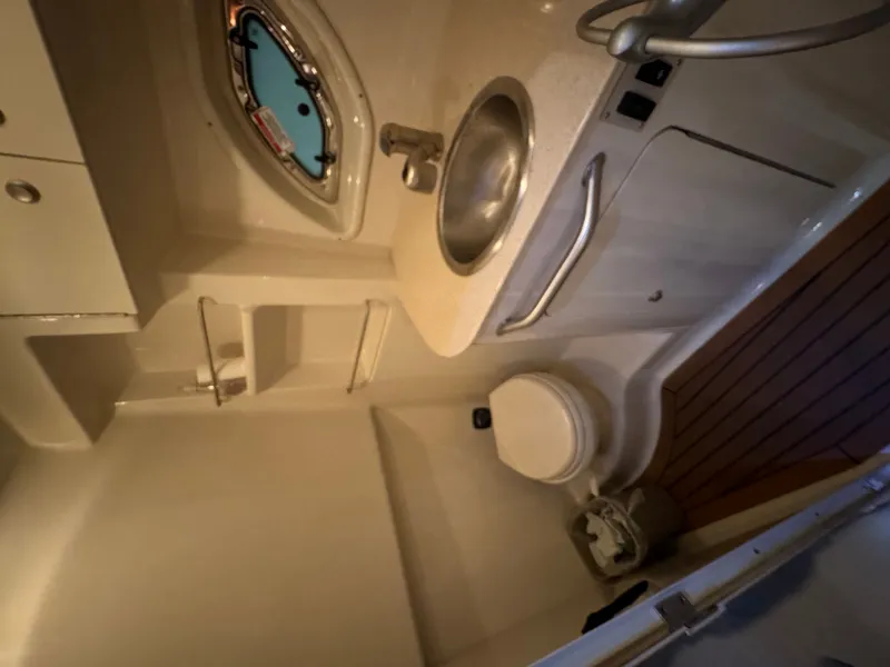 Slide: The Image of The image shows a boat bathroom with a sink, toilet, and porthole. - 26
