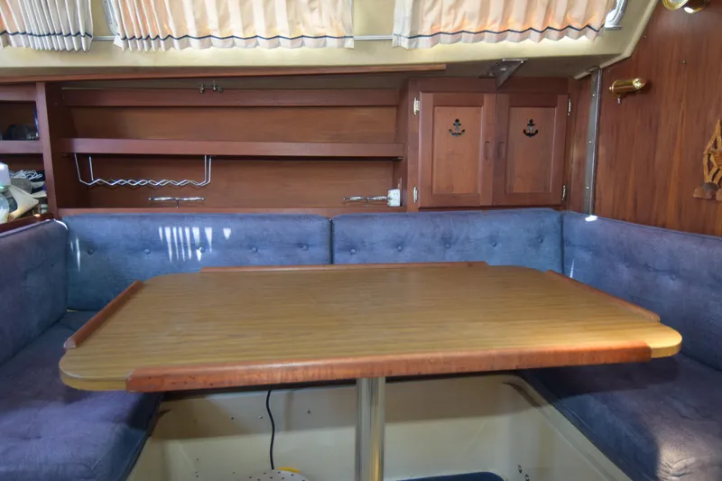 Slide: The Image of Interior of a 1991 Catalina 38 sailboat with wooden table and blue seating. - 9