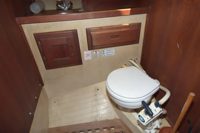 Slide: The Image of Bathroom interior of a 1991 Catalina 38 sailboat, featuring a marine toilet and wooden cabinetry. - 10