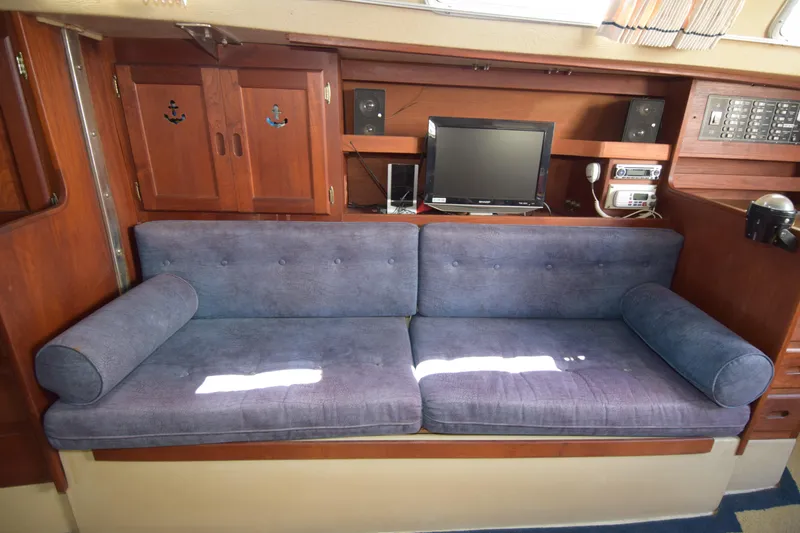 Slide: The Image of Interior of 1991 Catalina 38 sailboat with blue sofa, wooden cabinets, and electronics. - 2