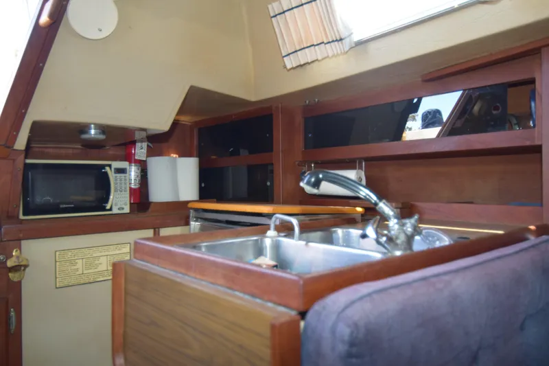 Slide: The Image of Interior of 1991 Catalina 38 sailboat galley with sink, microwave, and wooden cabinetry. - 5