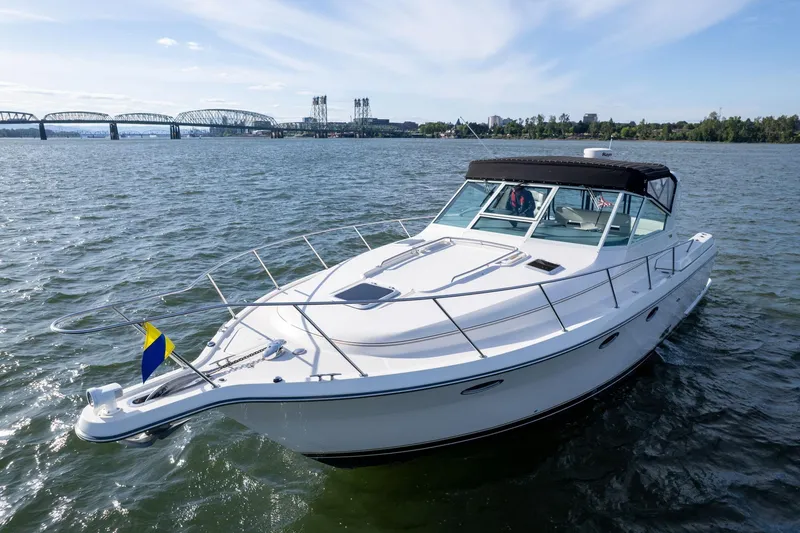 Slide: The Image of 1998 Tiara Yachts 3500 Express cruising on a scenic waterway near a bridge. - 2