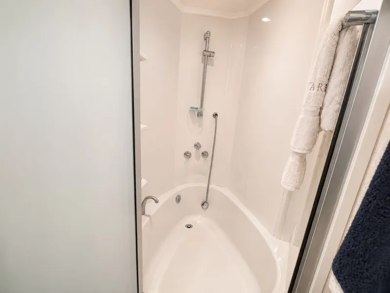 Slide: The Image of A sleek bathroom with a bathtub and shower combo, towels hanging on the wall. - 29