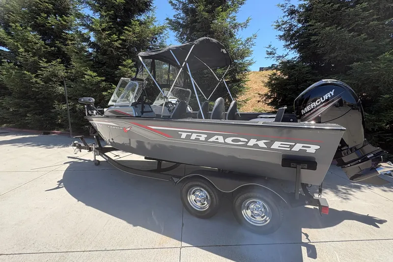 Slide: The Image of 2018 Tracker Targa V-18 Combo boat with Mercury engine on trailer, parked outdoors. - 2